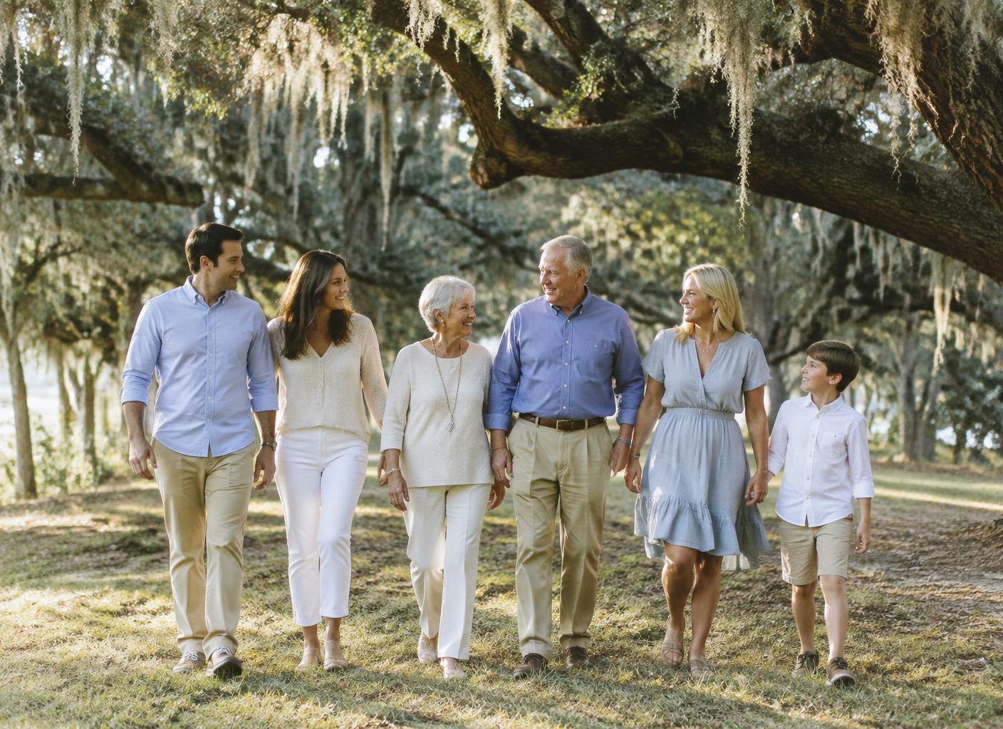 Three generations of a family walking beneath live oaks